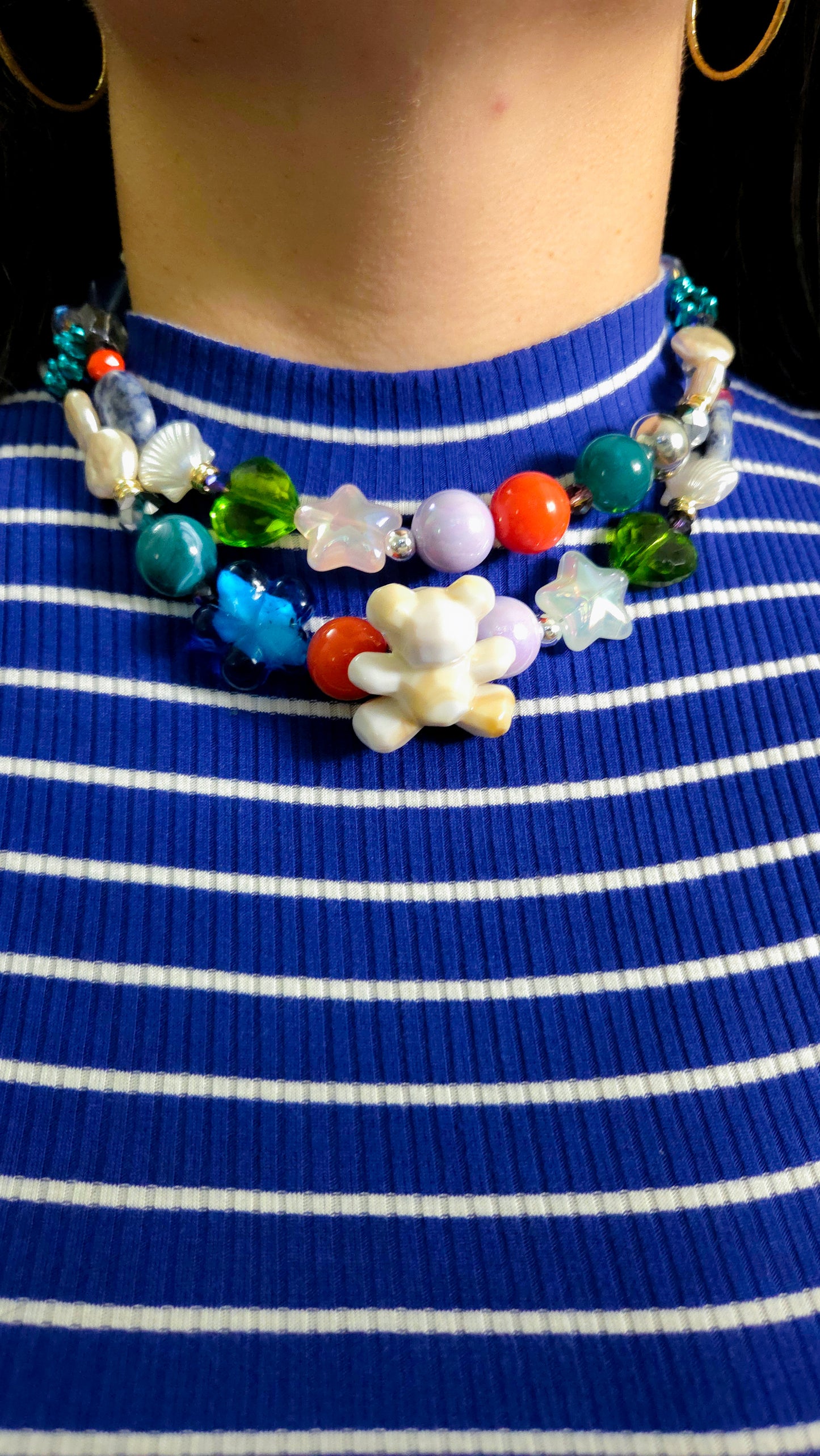 Layered eclectic necklace with acrylic and glass beads, pearls, stones, star shapes, hearts, and a pearlescent teddy charm β ocean-inspired maximalist jewelry by Lalabel.