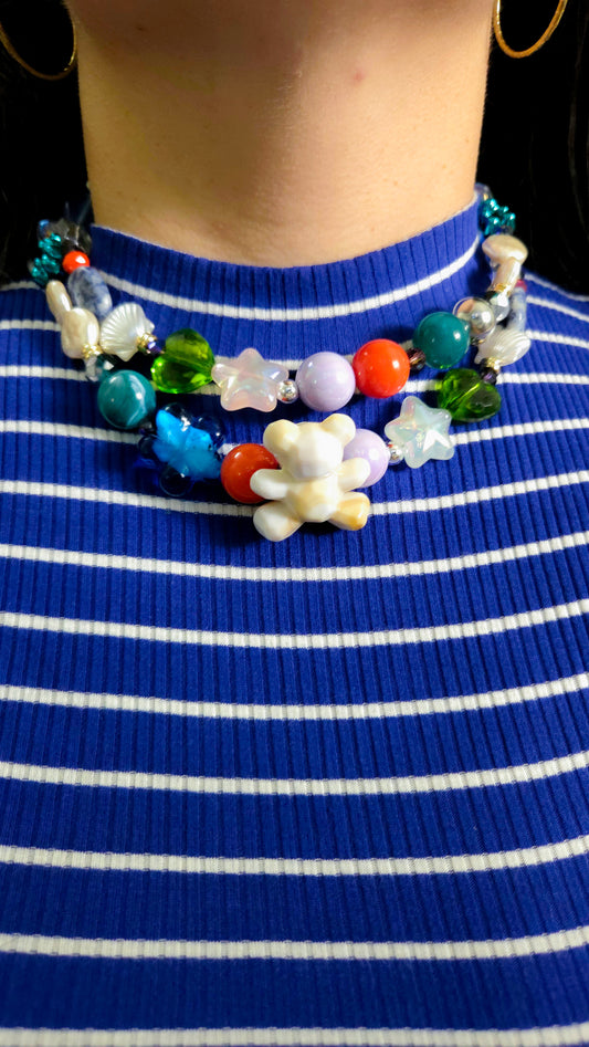 Layered eclectic necklace with acrylic and glass beads, pearls, stones, star shapes, hearts, and a pearlescent teddy charm – ocean-inspired maximalist jewelry by Lalabel.

