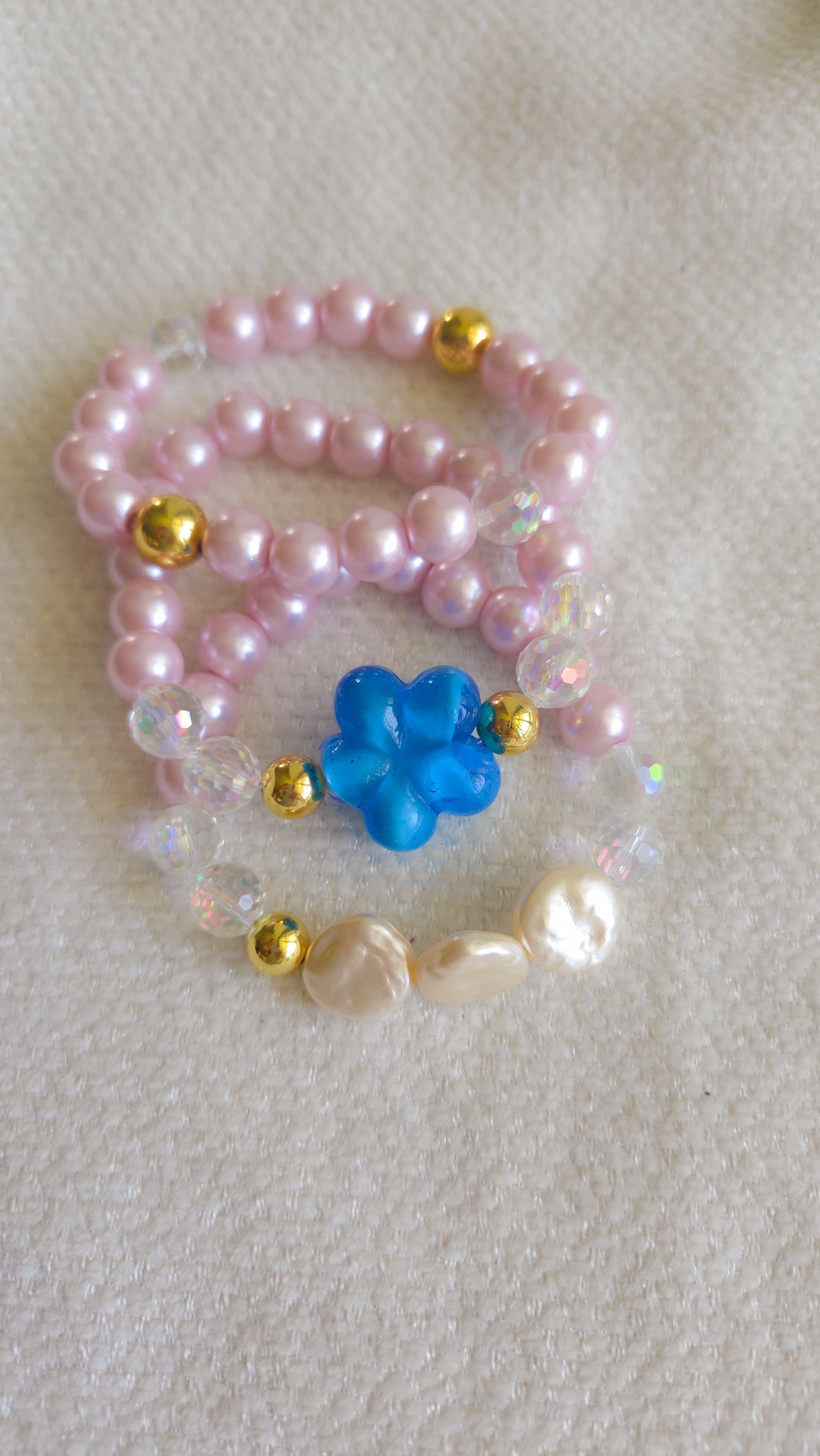 Pearl necklace with a blue flower pendant on a textured surface